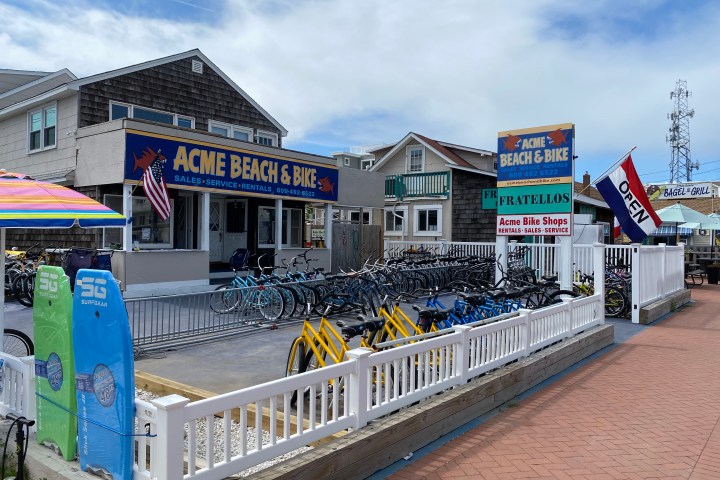 Bike rental shop with colorful surfboards, sign, and bikes on display outside.