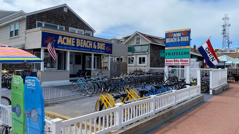 Bike rental shop with colorful surfboards, sign, and bikes on display outside.