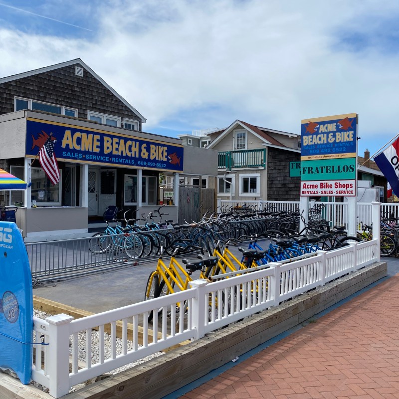 Bike rental shop with colorful surfboards, sign, and bikes on display outside.