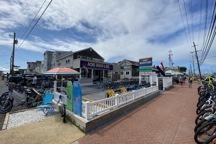 Bike shop with rentals and colorful umbrellas on a sunny street.