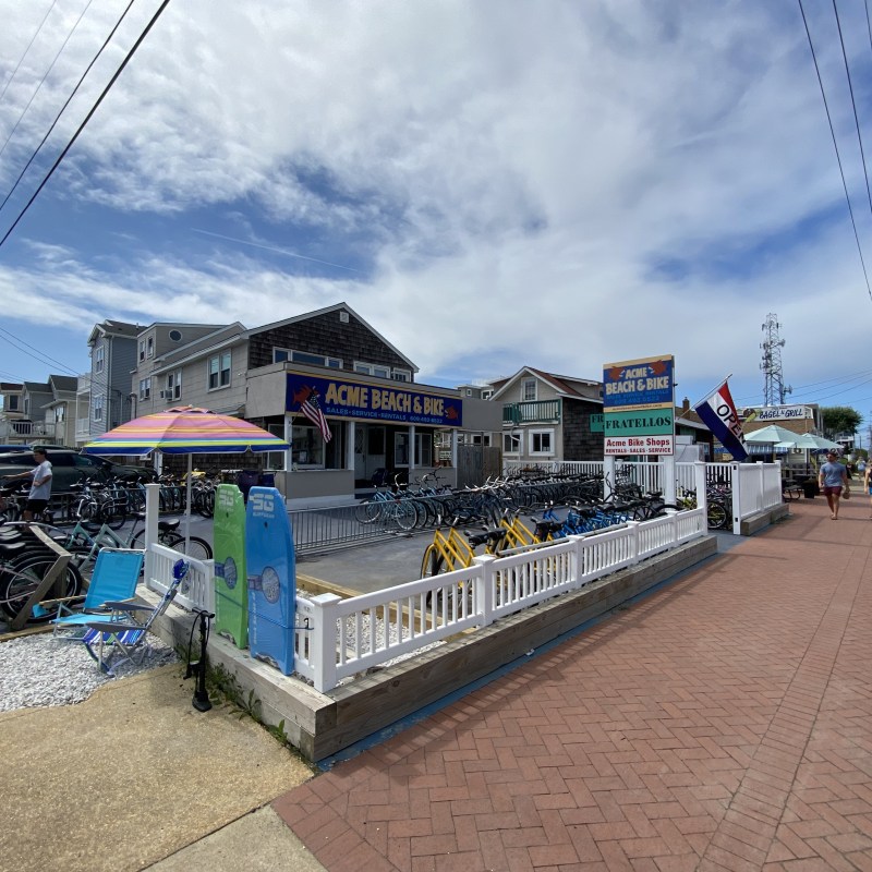 Bike shop with rentals and colorful umbrellas on a sunny street.