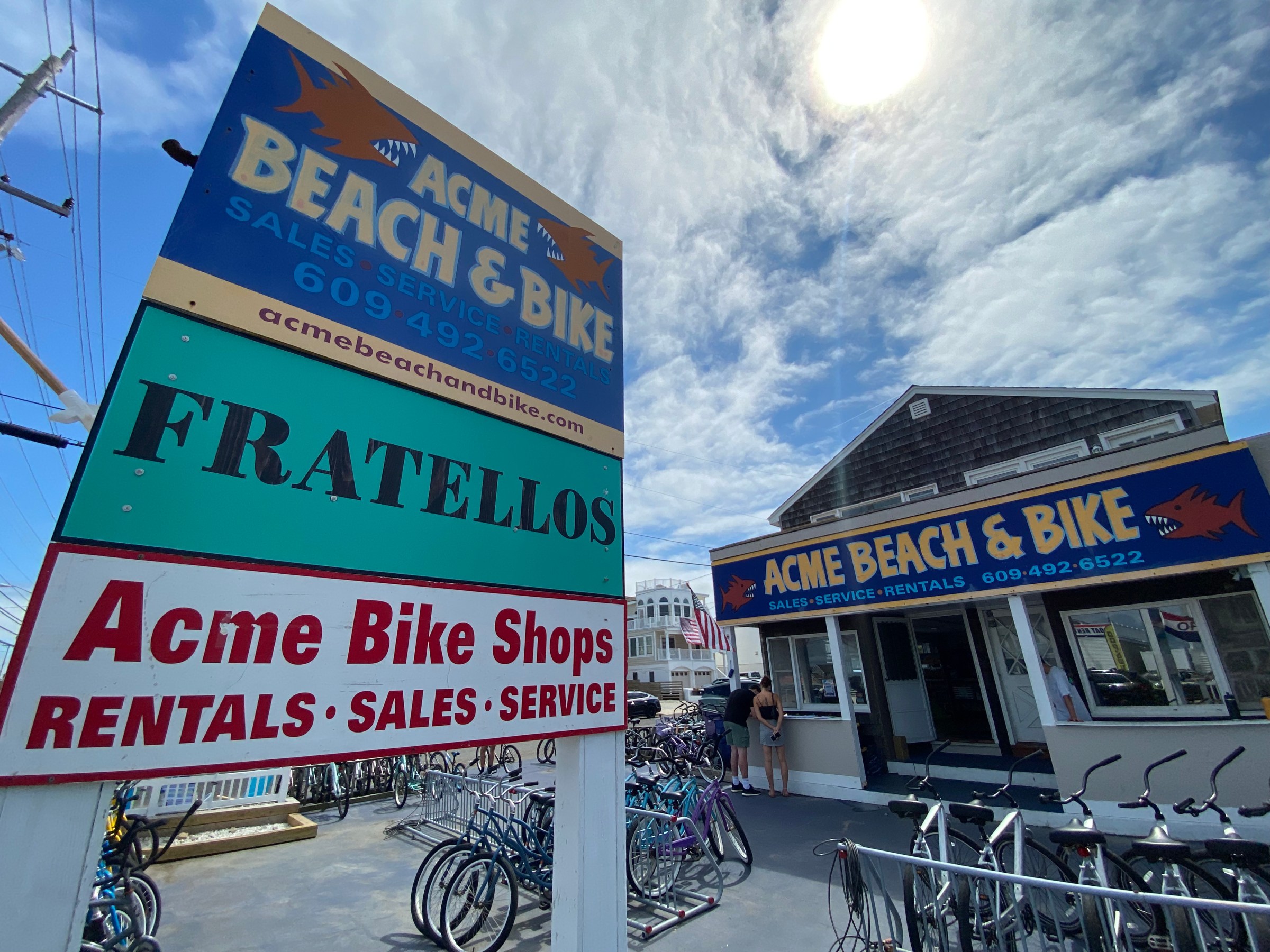 Outdoor view of Acme Beach & Bike store with bikes and signage under a sunny sky.