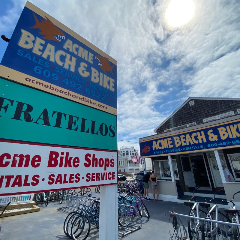 Outdoor view of Acme Beach & Bike store with bikes and signage under a sunny sky.