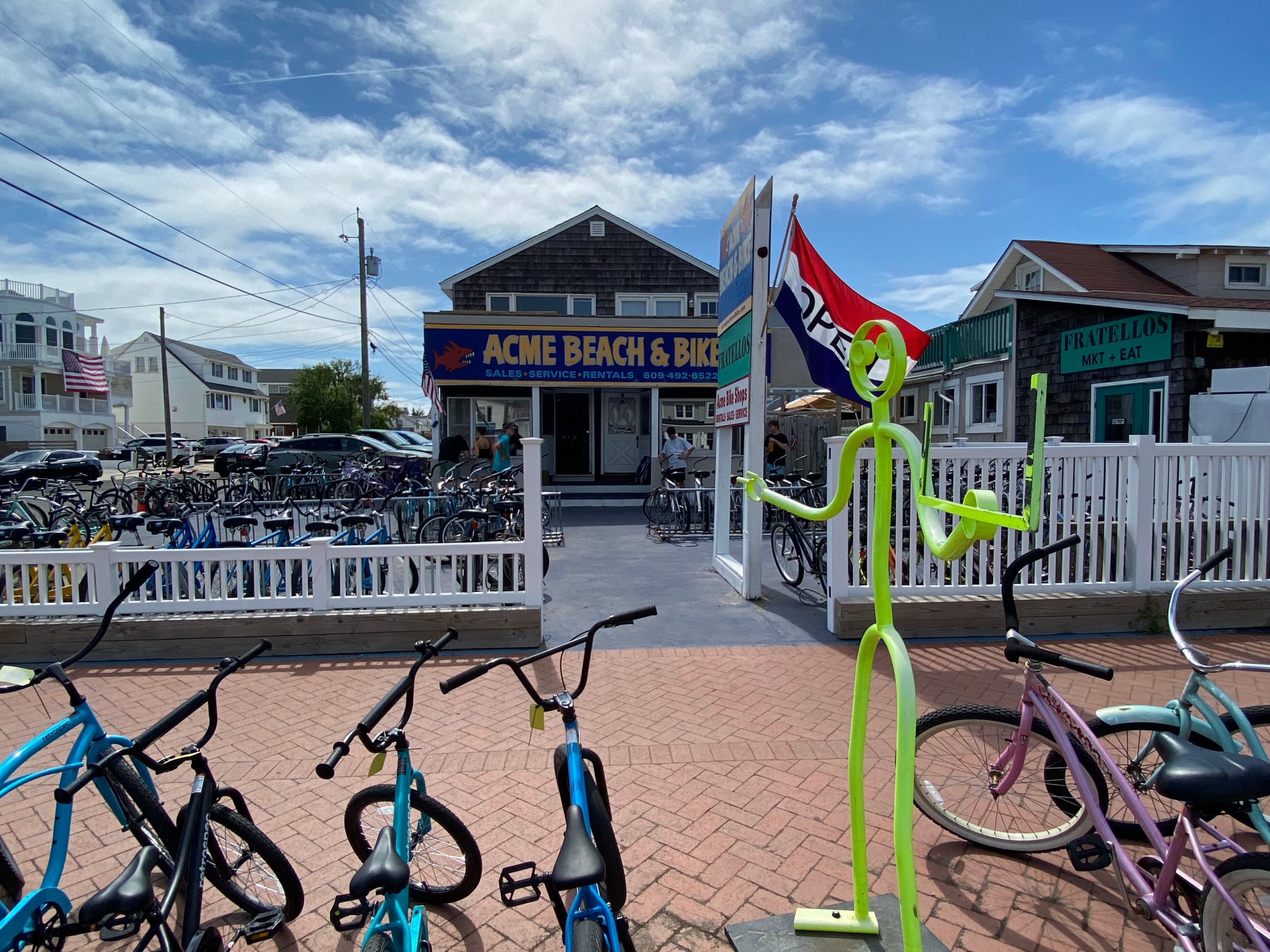 Bicycles parked outside a shop with a colorful sign and a clear sky overhead.