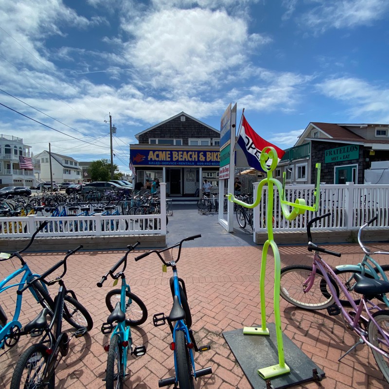 Bicycles parked outside a shop with a colorful sign and a clear sky overhead.