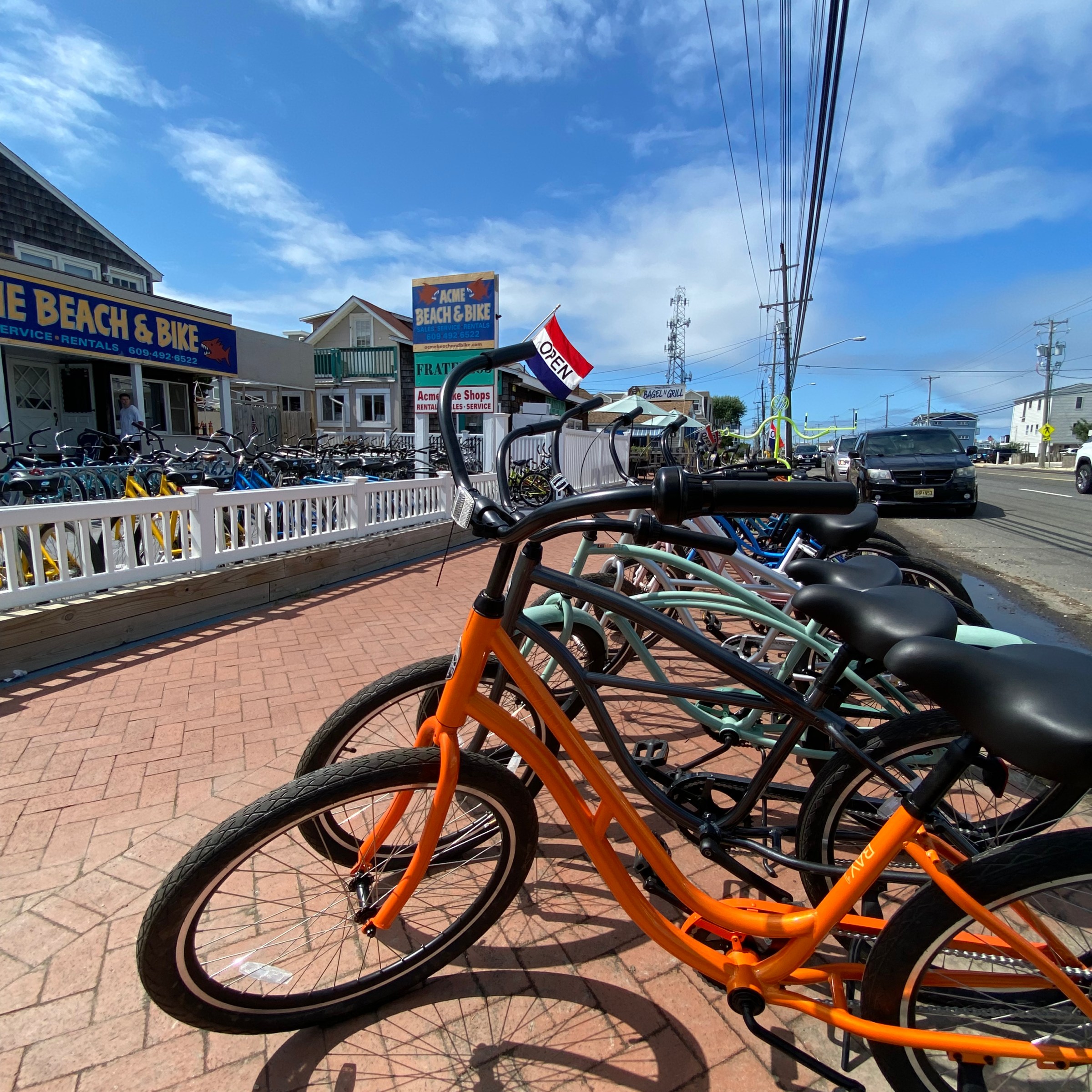 Row of bicycles outside a bike rental shop on a sunny day.