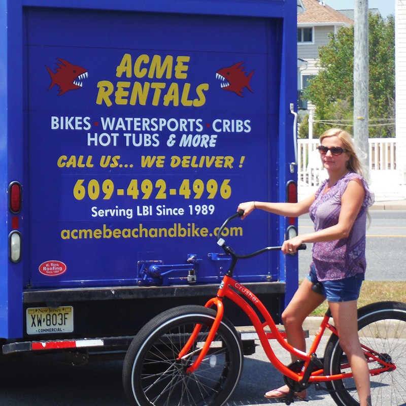 Woman with orange bike near blue rental truck with yellow text.