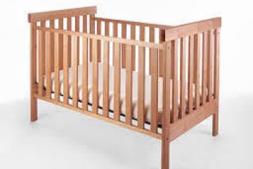 Wooden baby crib with slatted sides and a mattress, on a white background.